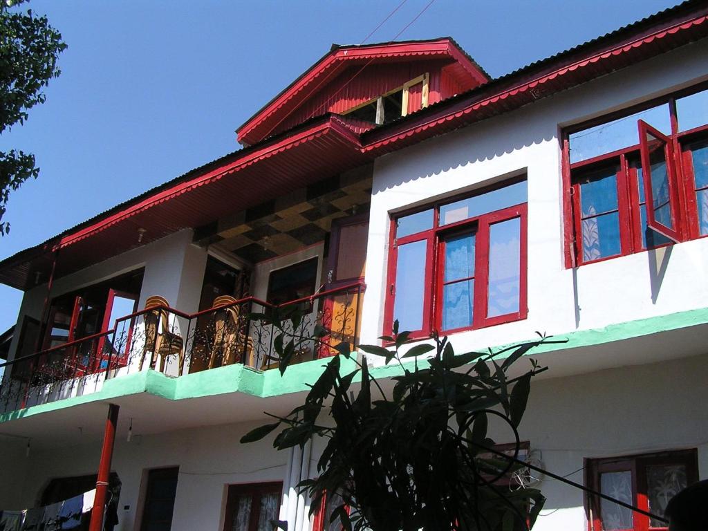 a house with red windows and a balcony at Howrah Guest House in Srinagar