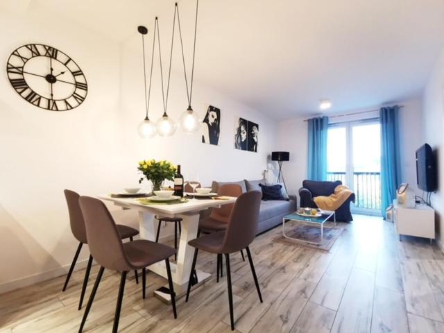 salon ze stołem i zegarem na ścianie w obiekcie Apartament nad morzem FABIO Kołobrzeg w Kołobrzegu
