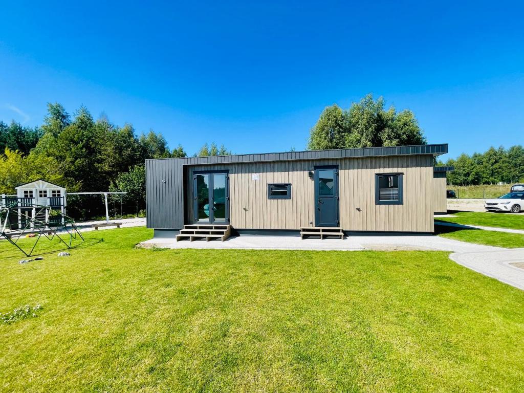 a small building with a grassy yard at New Corner Holiday Camp in Niechorze