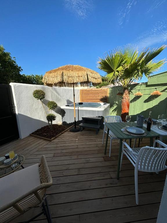 un patio avec un parasol, une table et des chaises dans l'établissement Charmante maisonnette à Angoulins, à Angoulins-sur-Mer