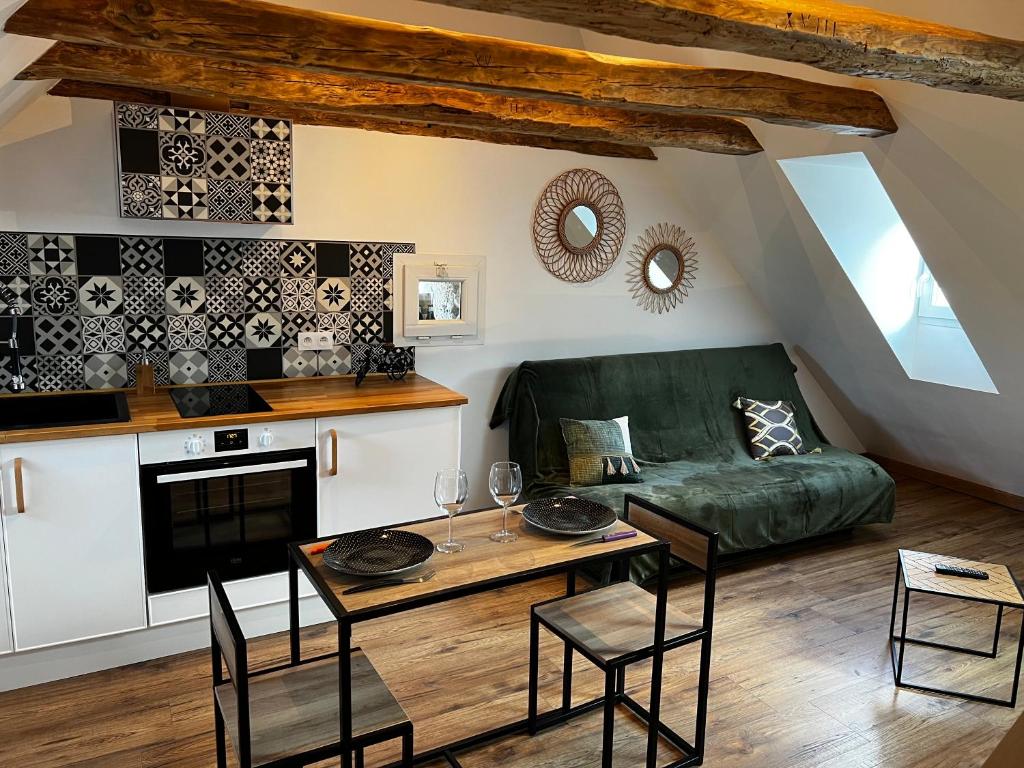 a living room with a green couch and a table at Cocon sous les toits du Gévaudan in Marvejols
