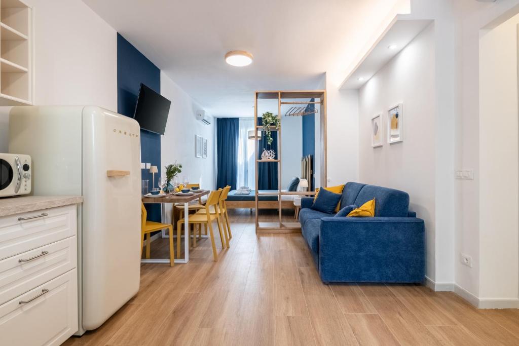 a kitchen and living room with a blue couch and a table at Taro's Blue Sea Apartment by Pleiades Home in Marina di Pisa