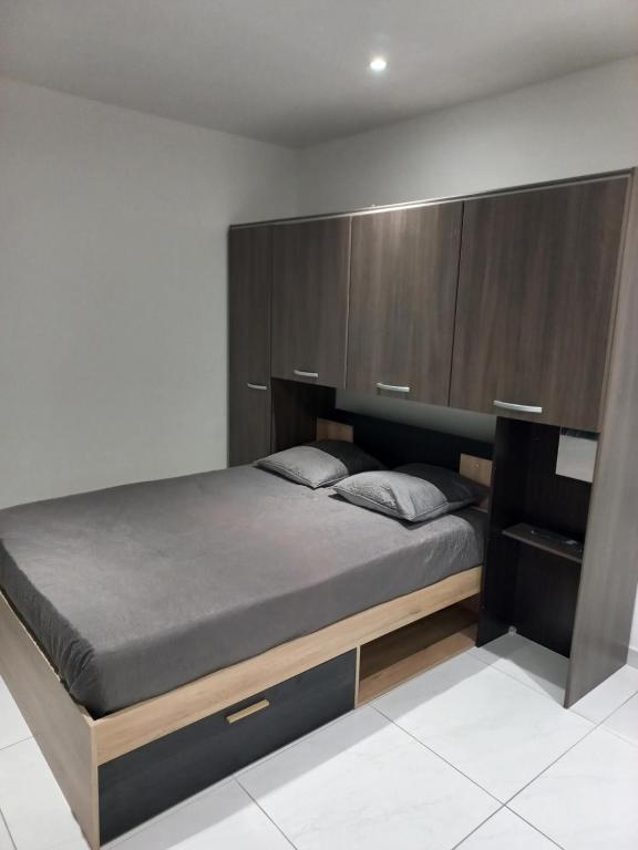 une chambre avec un lit avec une grande tête de lit en bois dans l'établissement Maisonnette entière, à Ivry-sur-Seine