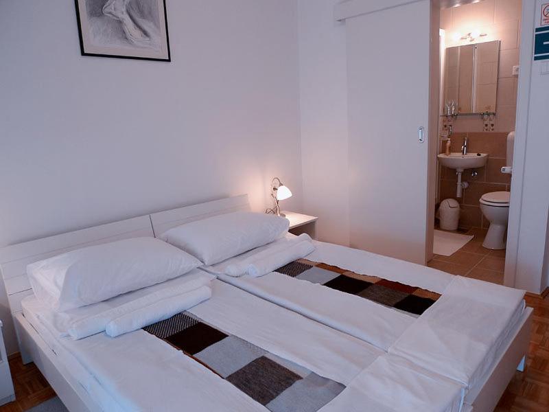 Cama blanca en habitación con baño en Guest House Kosec en Kutina