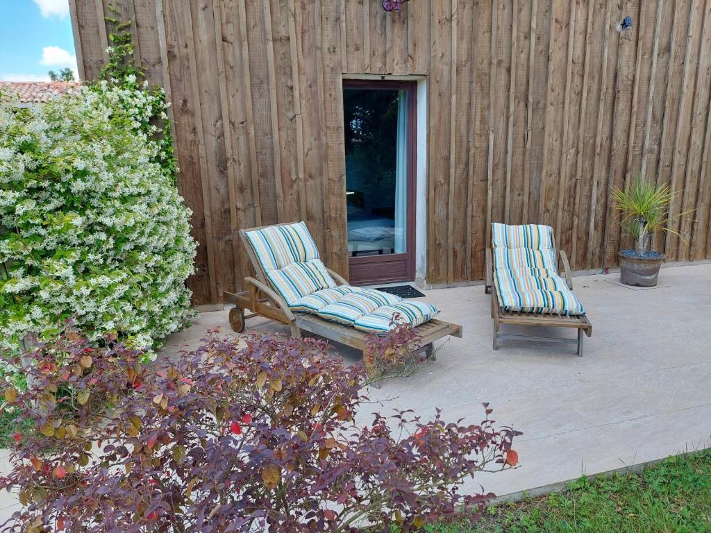two chairs and a bench on a patio at Gîte Cosy Grand confort dans un écrin de verdure in Agudelle