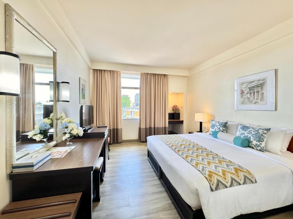 um quarto de hotel com uma cama grande e uma secretária em Phuket Merlin Hotel em Cidade Phuket