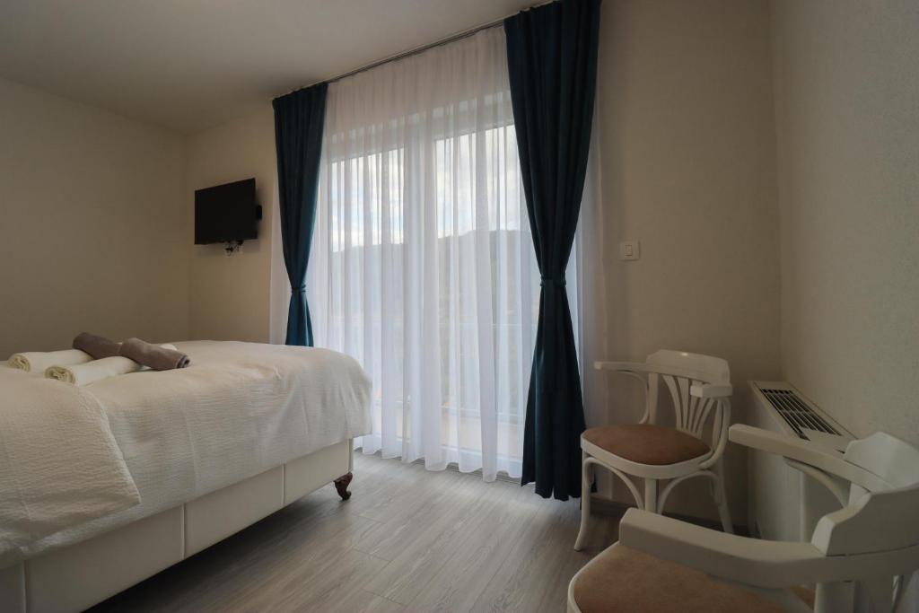 a bedroom with a bed and a chair and a window at Tadic apartments and rooms by the shore of Rama Lake in Prozor