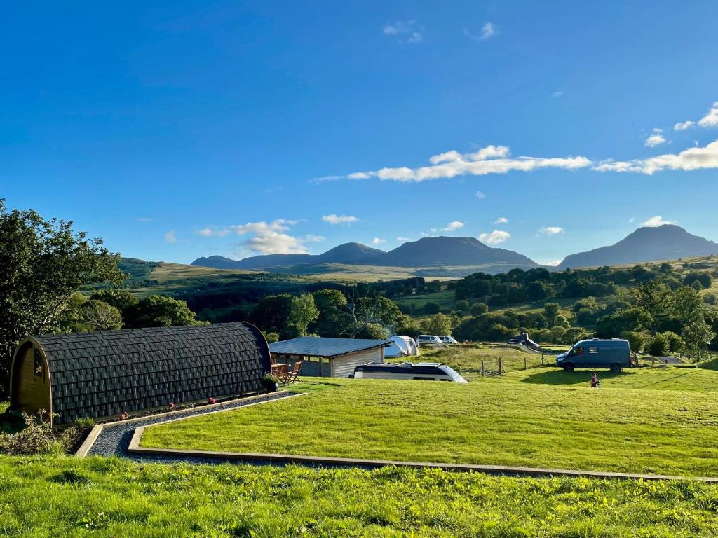 a field with a barn and mountains in the background at MTB Jumps View Pod in Trawsfynydd