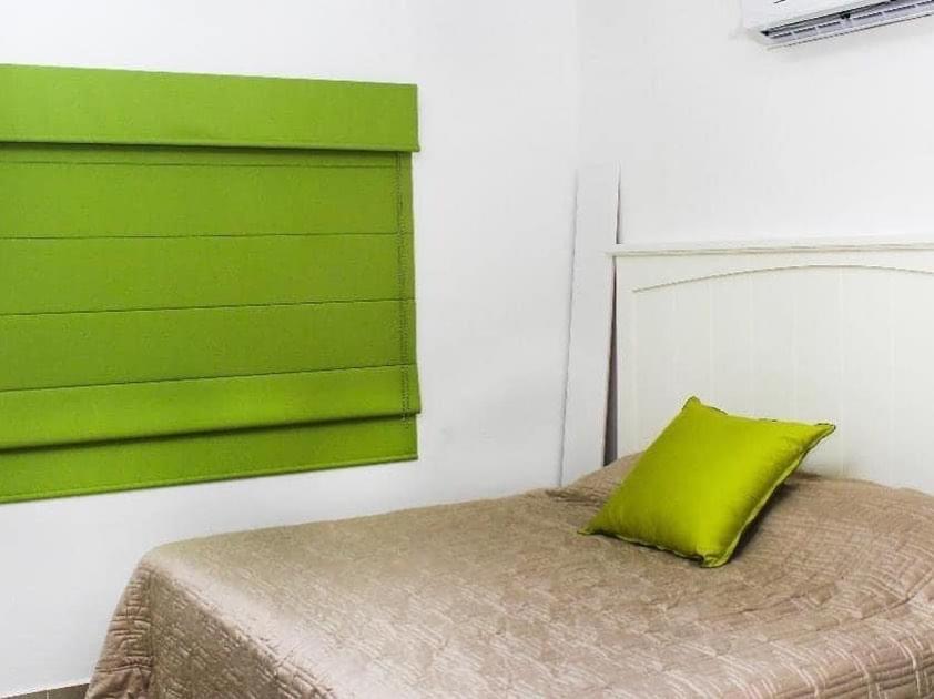 ein Schlafzimmer mit einem grünen Kissen auf einem Bett in der Unterkunft Casa Moderna Frente Alberca 3 min de la Playa Azul Pacifico in Mazatlán