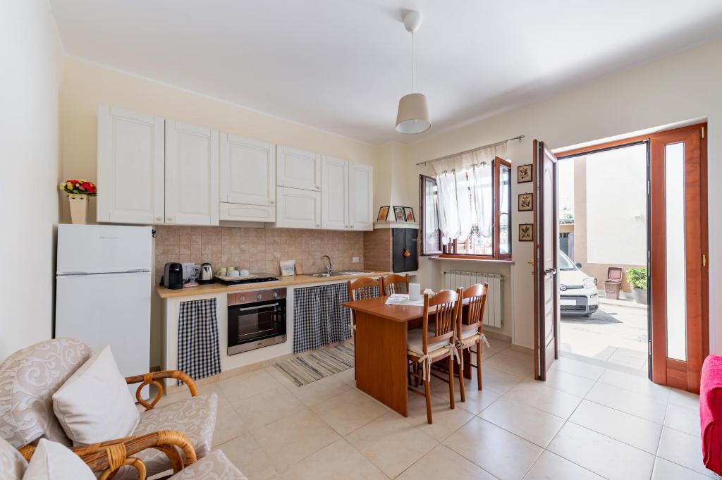 een keuken met witte kasten en een tafel en stoelen bij Villa Rosa by Rentbeat in Montalbano
