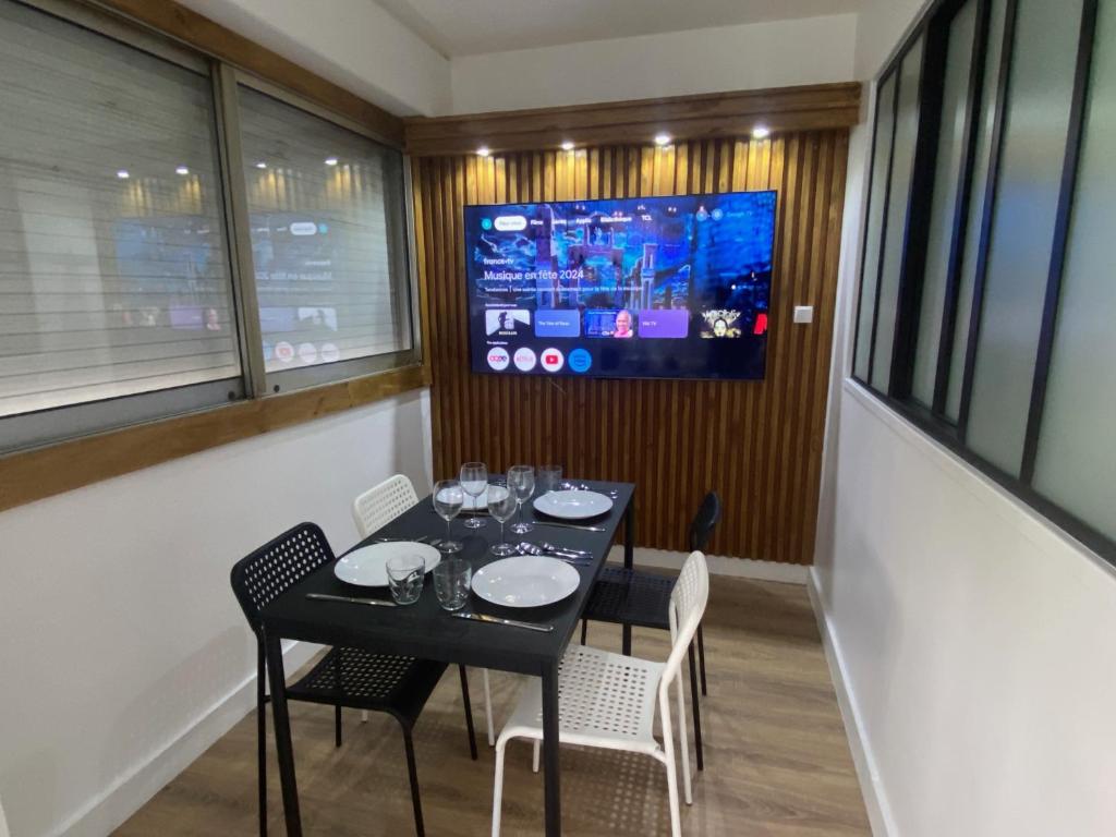 d'une salle à manger avec une table, des chaises et une télévision. dans l'établissement Appartement bassin de la villette, à Paris