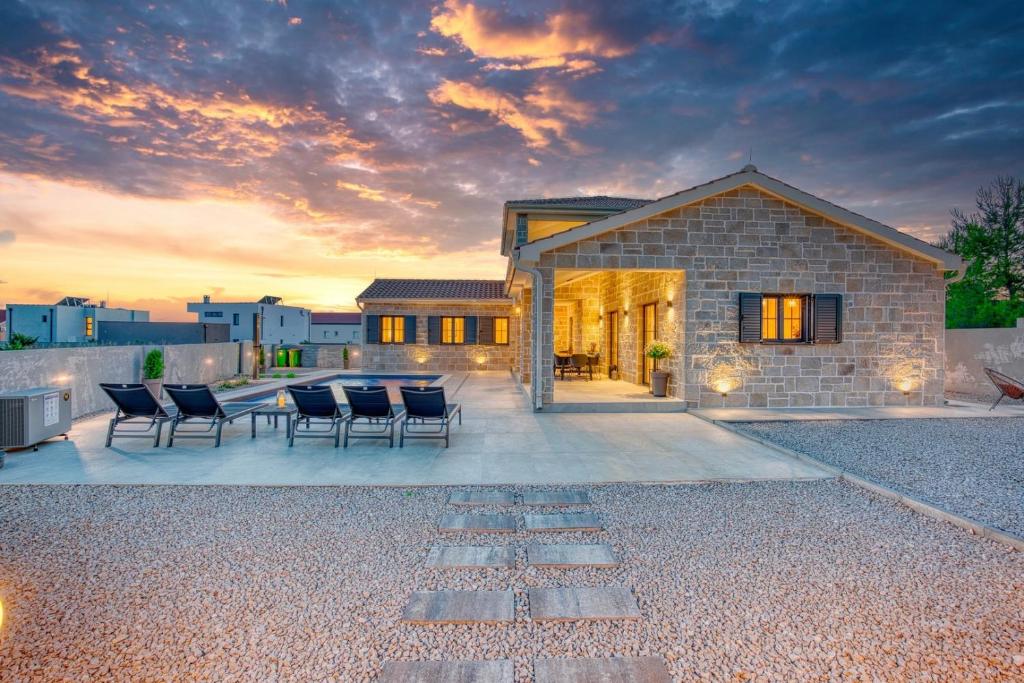 a house with chairs and a table in front of it at Luxury Villa Oliva Oliana heated pool 32m2 in Vrsi