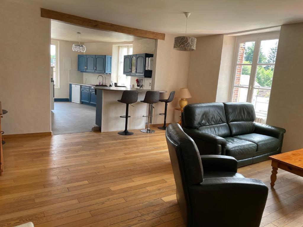 a living room with a leather couch and a kitchen at maison de ville dans le perche in Senonches