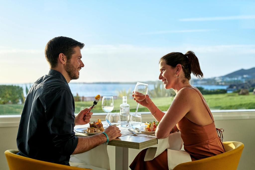a man and woman sitting at a table with wine glasses at Iberostar Selection Lanzarote Park in Playa Blanca