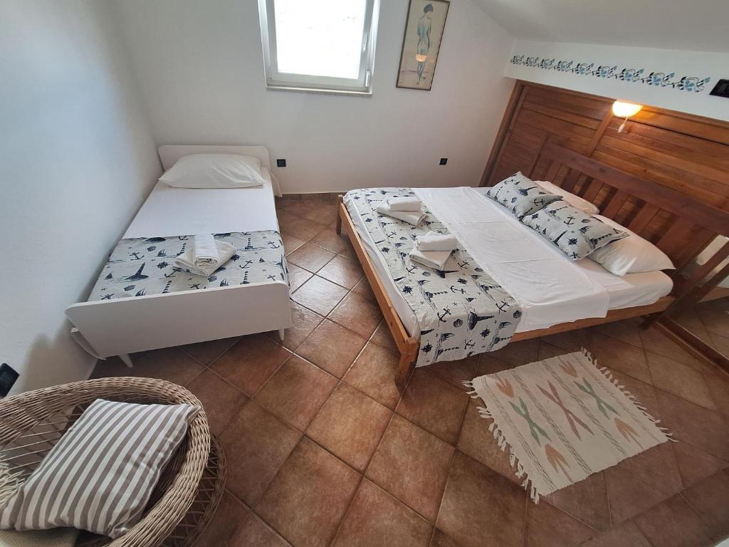 a small room with two beds and a chair at Loft Apartman in Krk