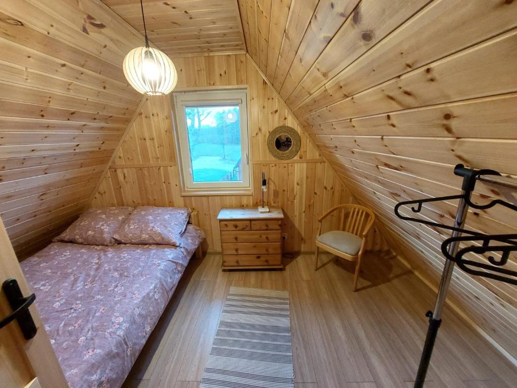 a bedroom with a bed in a wooden cabin at Kaszubskie Domki Nad Jeziorem Bluj in Głodowo