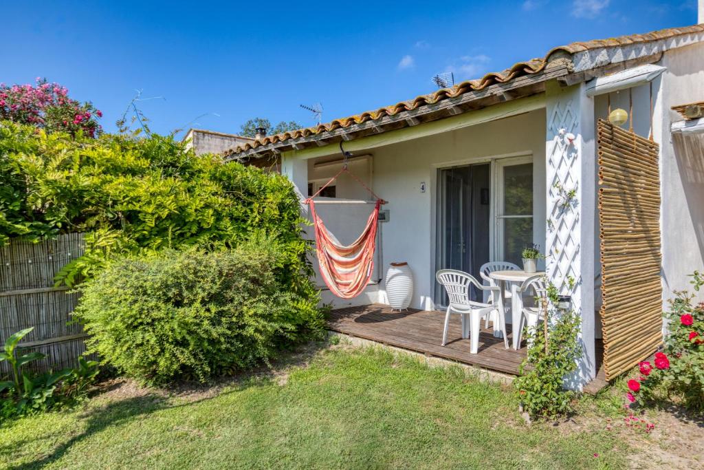 un patio avec une table et des chaises sur un porche dans l'établissement Mas des Cypres-Ensemble de 4 Mazets, à Saintes-Maries-de-la-Mer