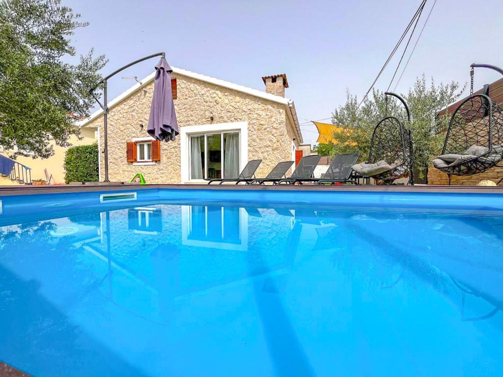a swimming pool with chairs and a house at MUSTRA House Zadar - Private Pool & Sauna in Zadar