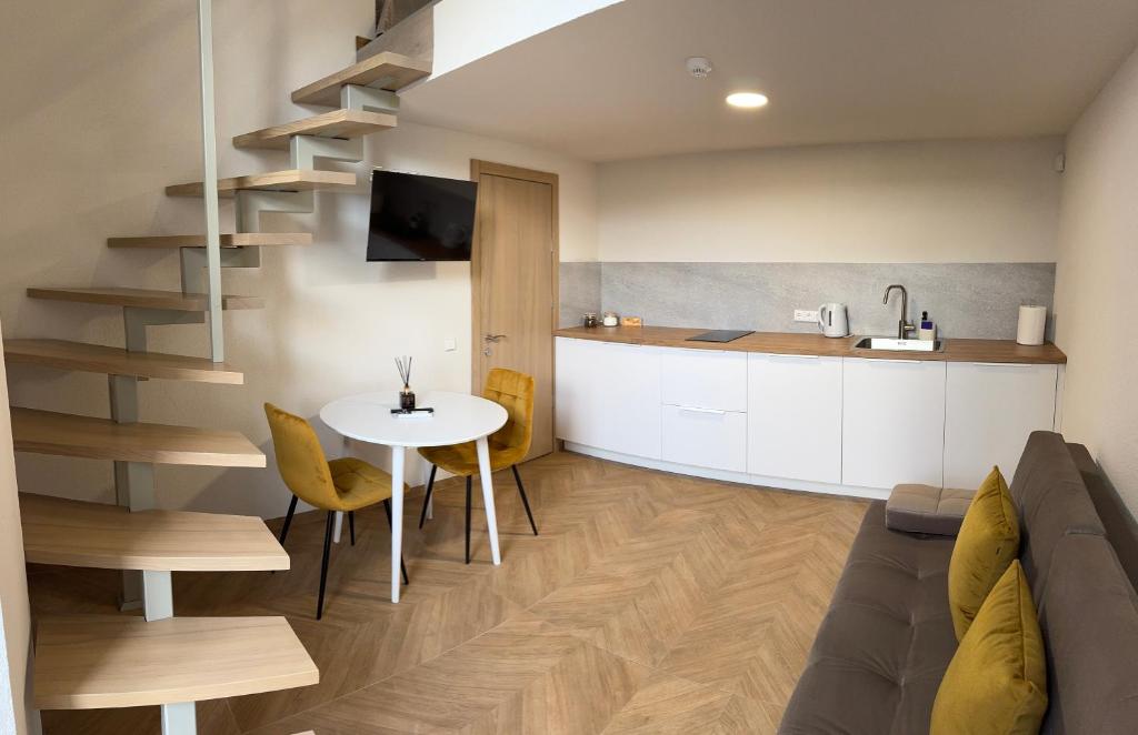 a living room with a staircase and a table and a kitchen at Loftas Smilga in Palanga
