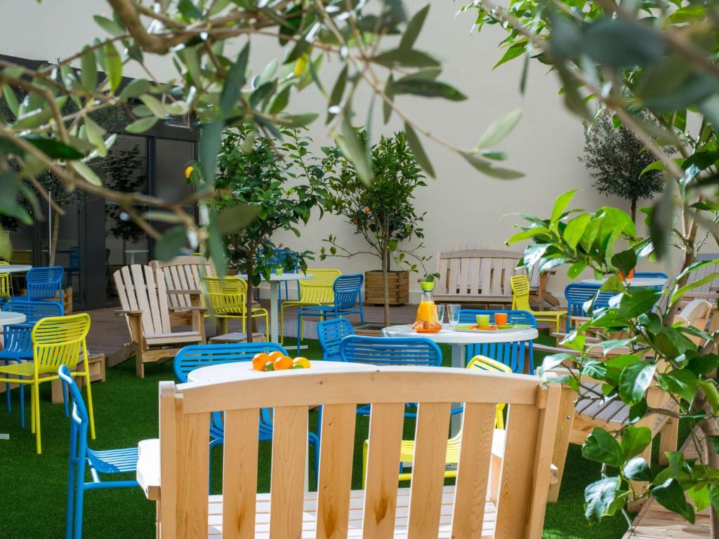 a patio with blue and yellow chairs and tables at Ibis Styles Nice Centre Gare in Nice