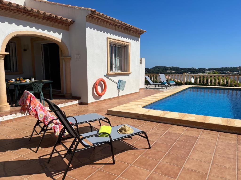 a patio with a chair next to a swimming pool at Villas Monte Jávea - BTB in Jávea