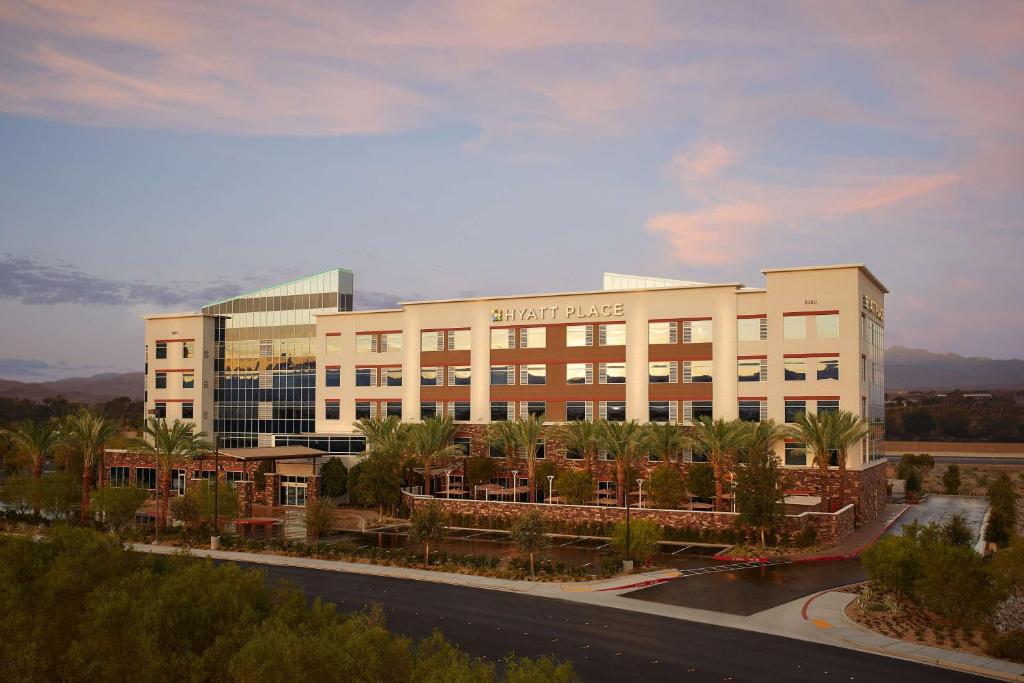 a large white building with palm trees in front of it at Hyatt Place Las Vegas at Silverton Village in Las Vegas