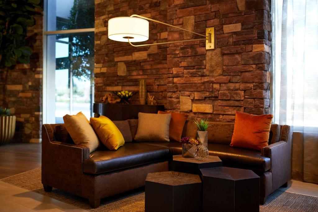 ein Wohnzimmer mit einem Ledersofa und einer Ziegelwand in der Unterkunft Hyatt Place Las Vegas at Silverton Village in Las Vegas