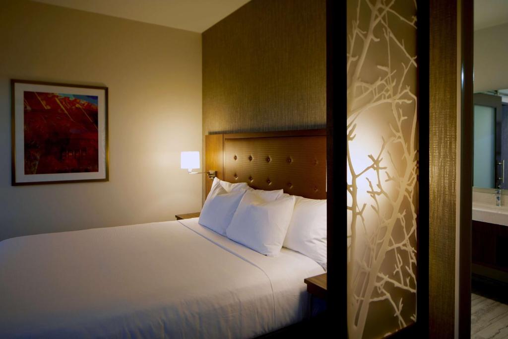 ein Hotelzimmer mit einem Bett mit weißen Kissen in der Unterkunft Hyatt Place Las Vegas at Silverton Village in Las Vegas