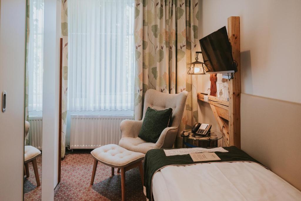 een kamer met een bed, een stoel en een televisie bij Boutiquehotel Stadthalle in Wenen