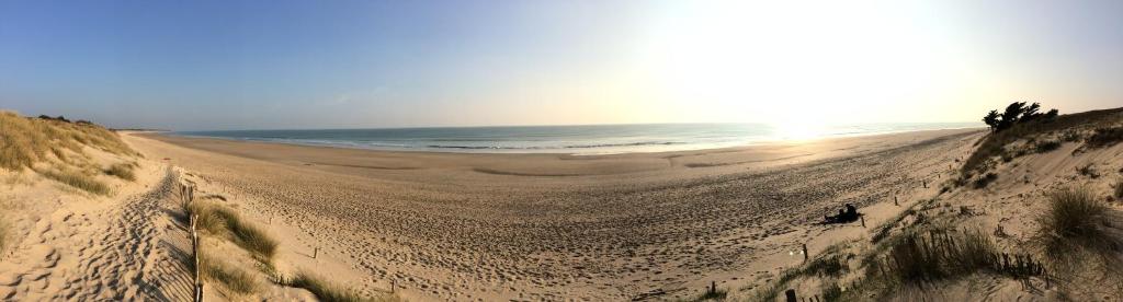 a sandy beach with the ocean in the background at L'Olivier de Milou in Le Bois-Plage-en-Ré