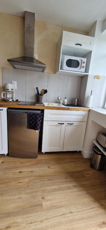 une cuisine avec des armoires blanches, un évier et un micro-ondes dans l'établissement Le Cosy, à Caraman