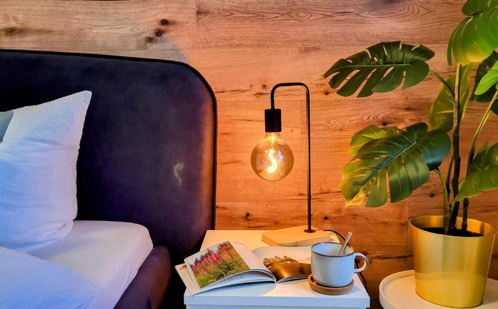 a bedroom with a bed and a table with a book and a lamp at HIRSCH FeWo Brocken - Parkplatz - Zentral in Bad Harzburg