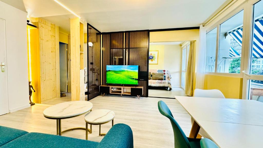 un salon avec une télévision, une table et des chaises dans l'établissement Pinky Bird Paris 13, à Paris