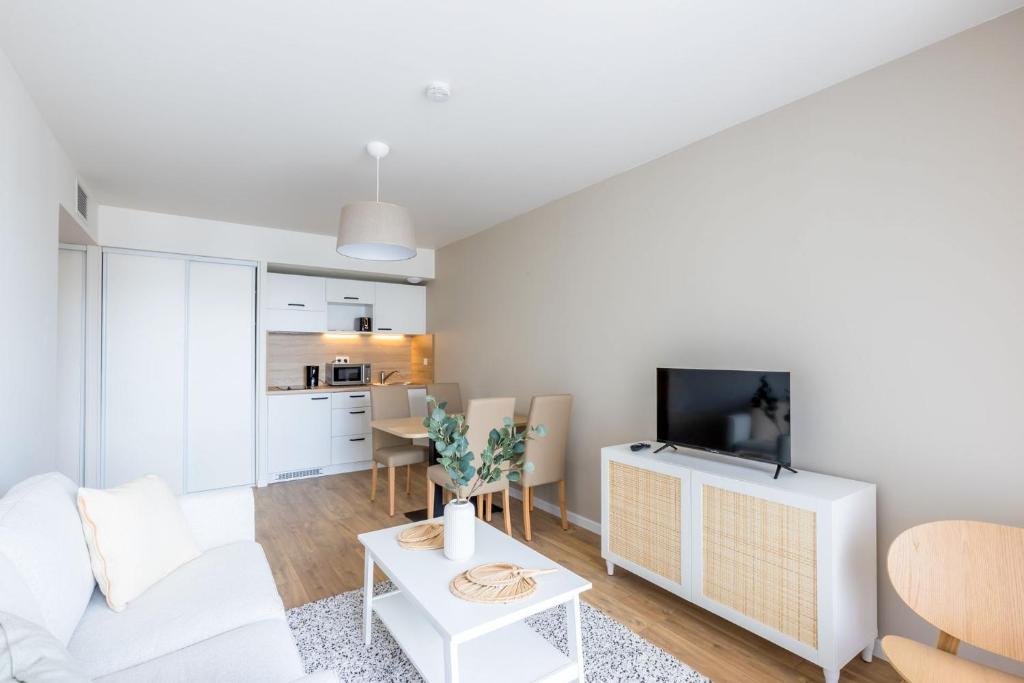 un salon avec un canapé blanc et une télévision dans l'établissement OVELIA Troyes - Le Carré Madeleine, à Troyes
