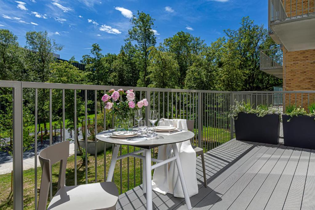 un patio con una mesa con flores. en cohost I New Apt w-Balcony I Air Condition I Free Parking & Netflix I By Botanical Park, en Kaunas