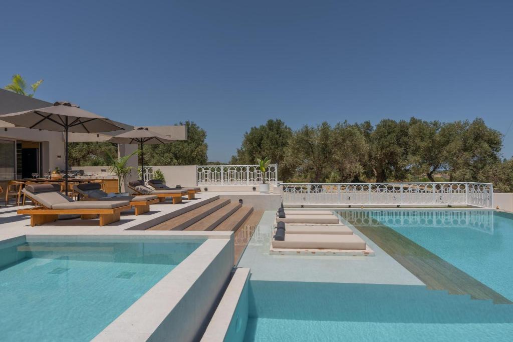 a swimming pool with benches and tables and a swimming pool at Bliss Villas in Rethymno Town