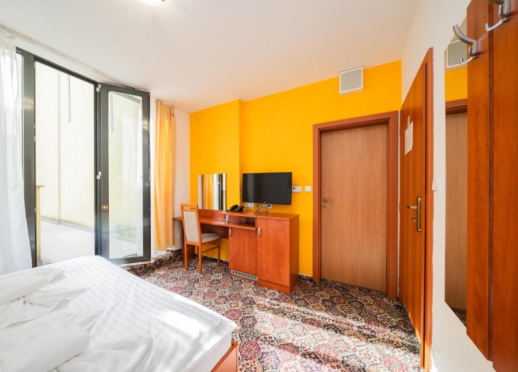 a room with a bed and a desk with a television at City Central De Luxe in Prague