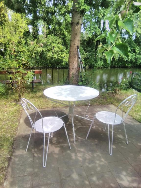 une table et deux chaises assises à côté d'un arbre dans l'établissement La petite maison au bord de l'Orne, à Putanges
