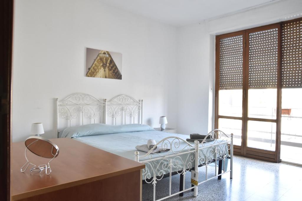 a white bedroom with a bed and a desk and a window at VERETO apartaments Lecce in Lecce