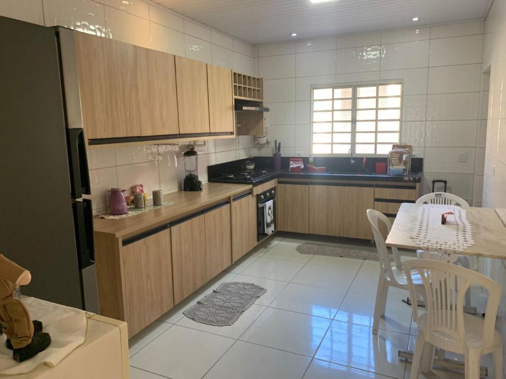 una cucina con mobili in legno e un tavolo con sedie di Casa de mãe Completa! a Marília
