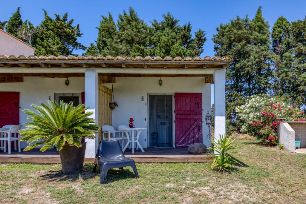 a chair in front of a house with a red door at Mas des Cypres - Mazet 9 in Saintes-Maries-de-la-Mer