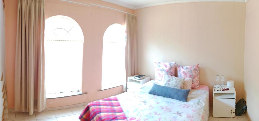 a bedroom with a bed and two large windows at 54 Martjie laan in Brits