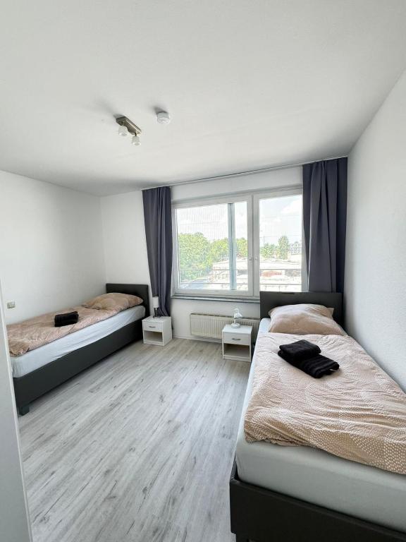 sypialnia z dwoma łóżkami i dużym oknem w obiekcie Frühling Apartment w mieście Bergisch Gladbach
