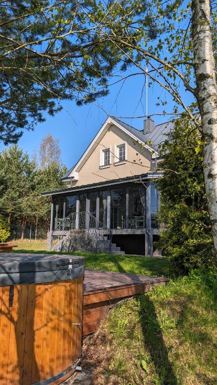 a house with a wooden deck in the yard at Vila Vynuogyne in Paberžė