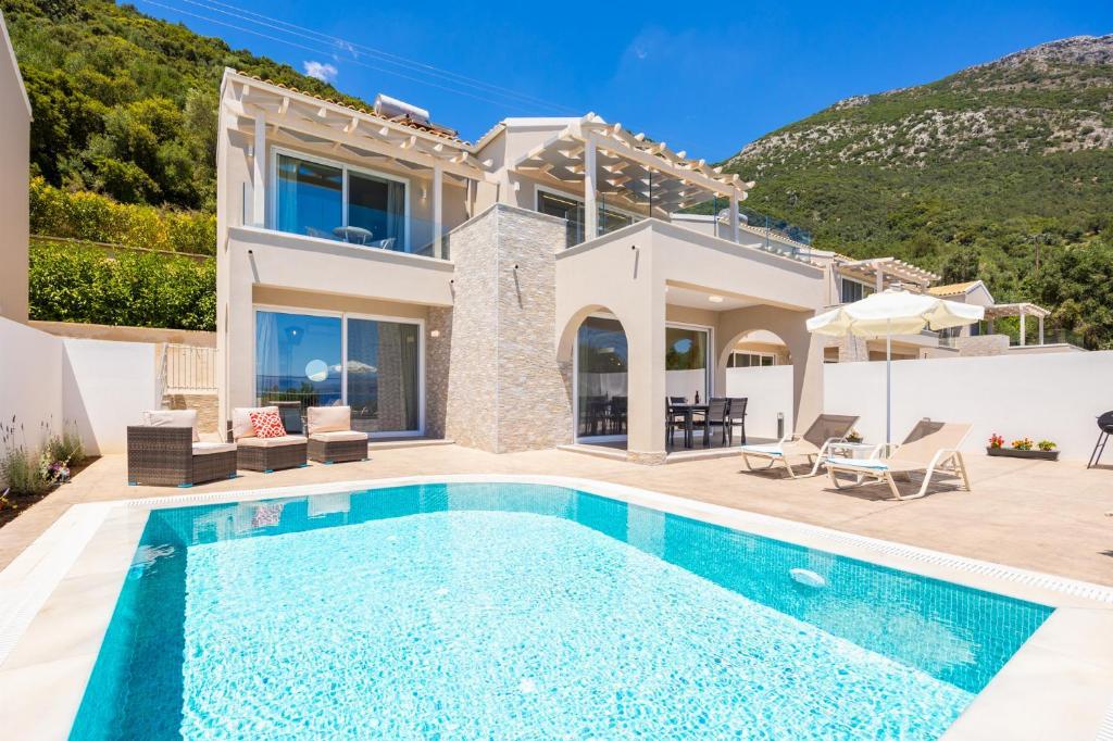 a villa with a swimming pool in front of a house at Villa Alora in Barbati