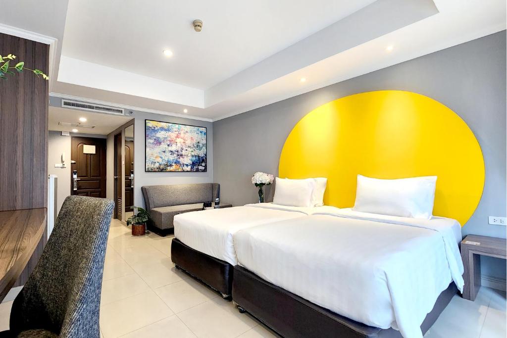 a bedroom with a large bed and a yellow wall at FuramaXclusive Sukhumvit in Bangkok