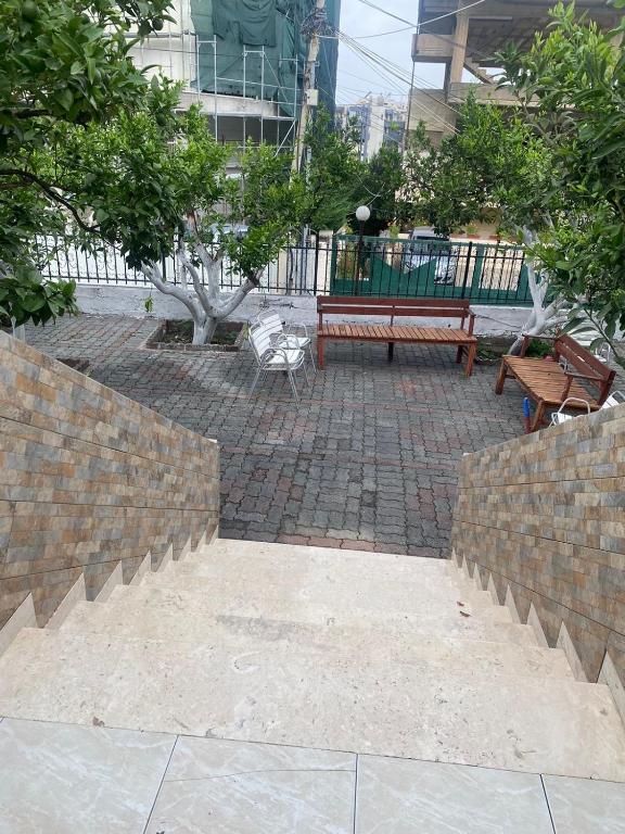 un parque con banco, árboles y acera en Aulona's Garden, en Vlorë