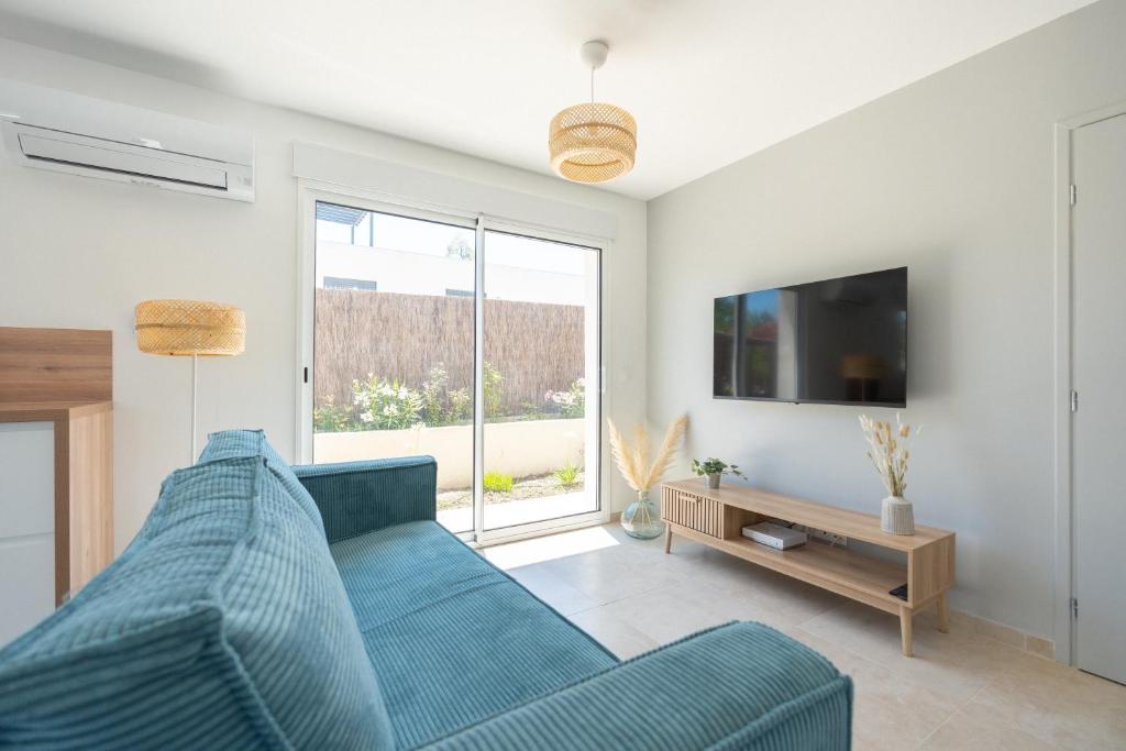 a living room with a blue couch and a tv at Villa Lavande in Marignane