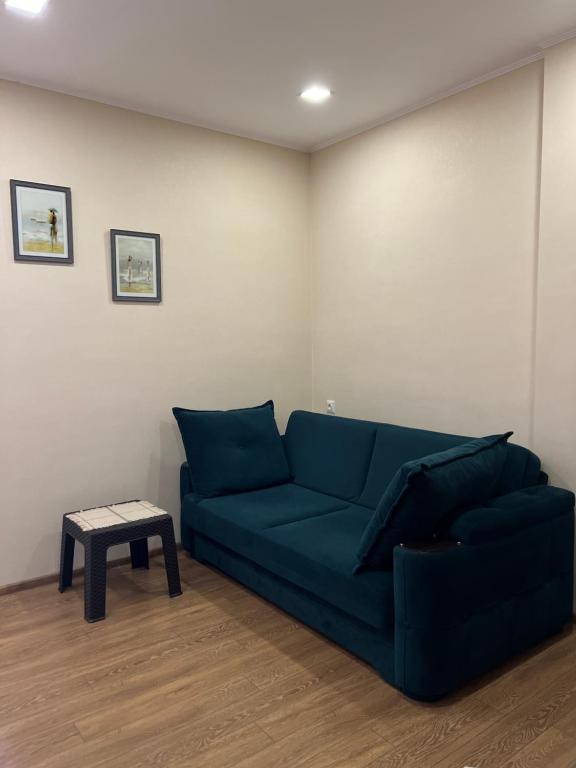 a living room with a blue couch and a table at Cosy apartment near the sea in Batumi