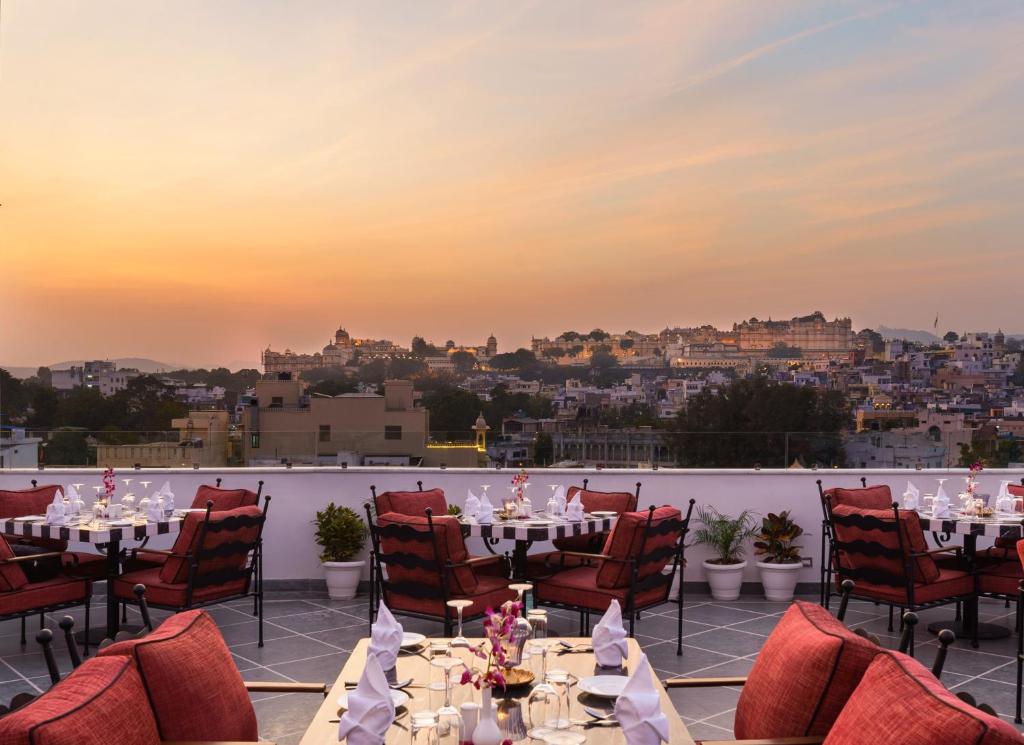 a restaurant with tables and chairs with a view of the city at Chunda Haveli in Udaipur